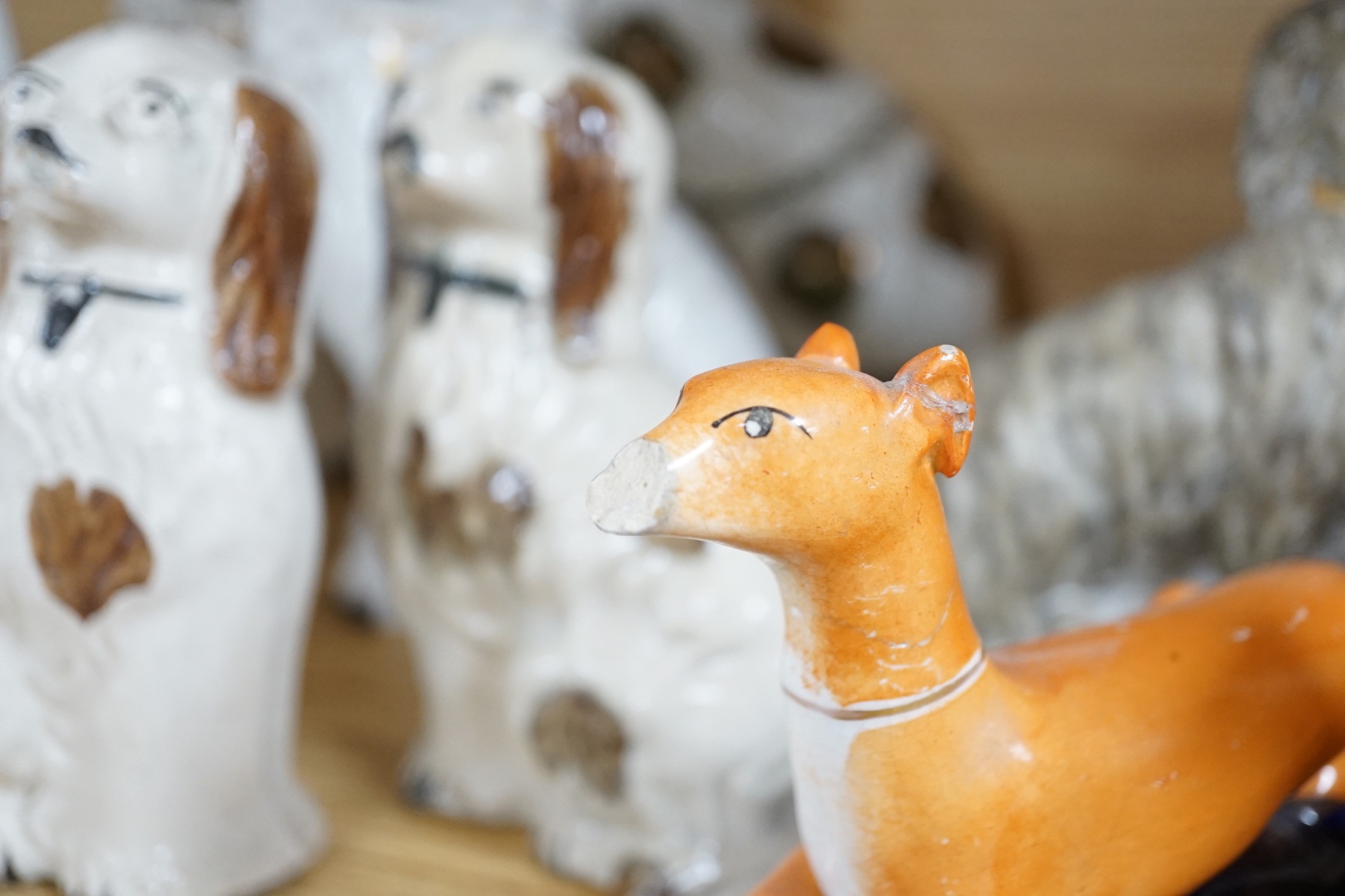 A mixed collection of mostly Staffordshire pottery models of recumbent dogs, hounds, etc. to include Dalmatians- 19.5cms high